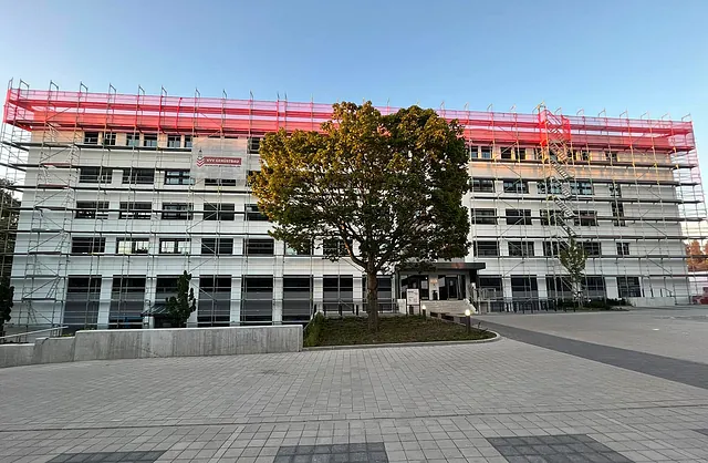 Mehrgeschossige Gebäudefassade der Marzipanfabrik Hamburg mit Arbeitsgerüst, Gerüsttreppe und roten Schutznetzen für Sanierungsarbeiten.