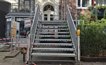 Temporäre Gerüsttreppe aus Metall vor einem Gebäude für sicheren Baustellenzugang und Personentransport beim Gerüstbau in Hamburg.